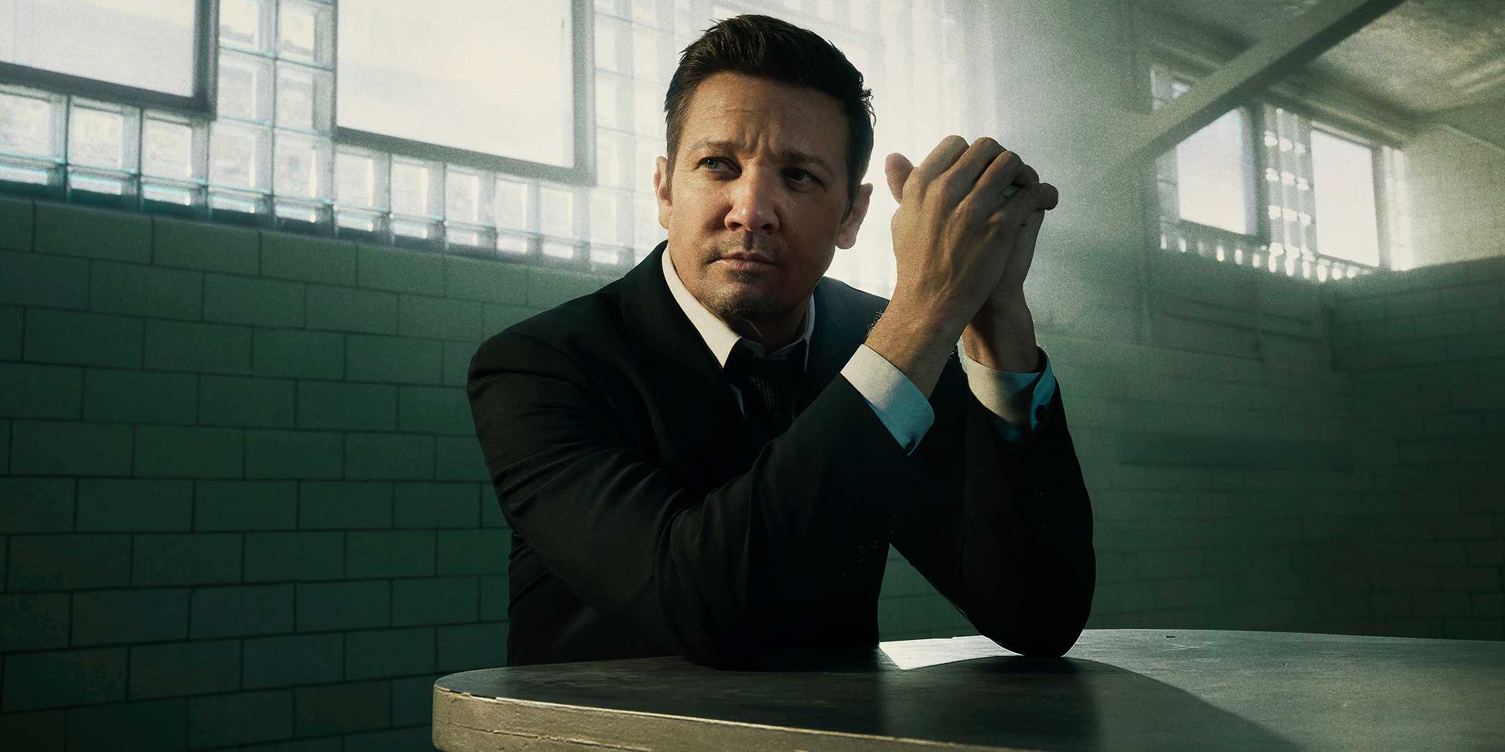 Mike de Jeremy Renner sentado à mesa e olhando para o lado em Mayor of Kingstown temporada 4