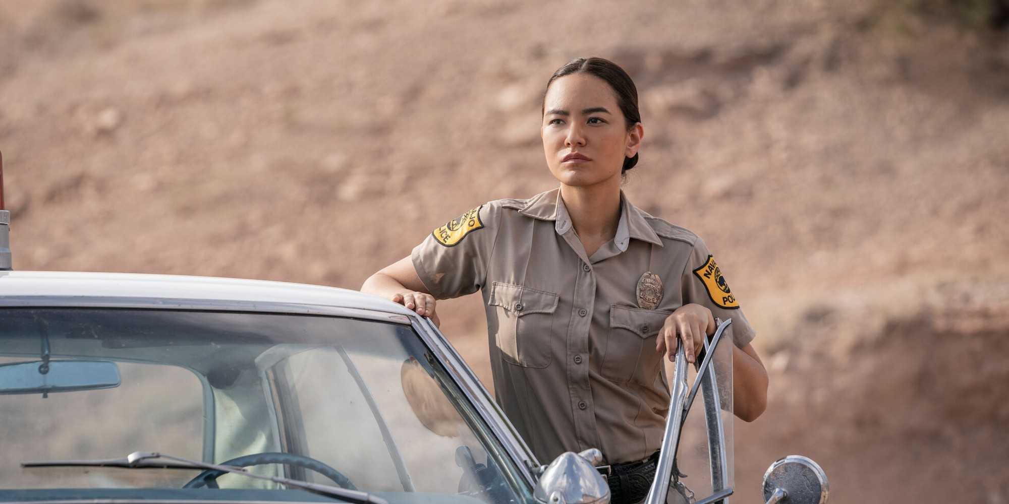 Dark Winds: Morte de Gordo Sena muda a 5ª temporada Bernadette Manuelito (Jessica Matten) standing outside a cop car in Dark Winds