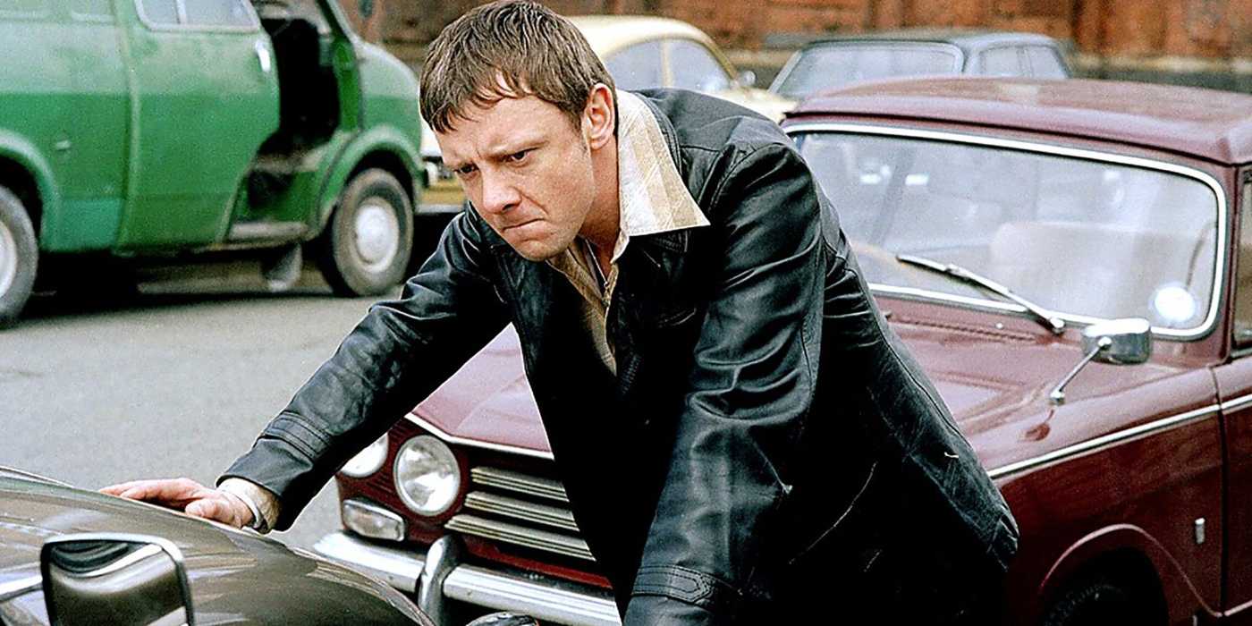 Sam Tyler leaning against a car hood with an angry expression in Life on Mars.