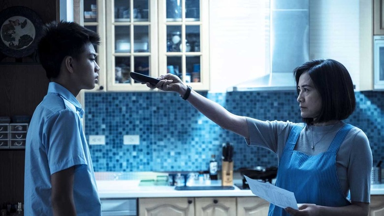 A mother holding up a remote to her son in On Children