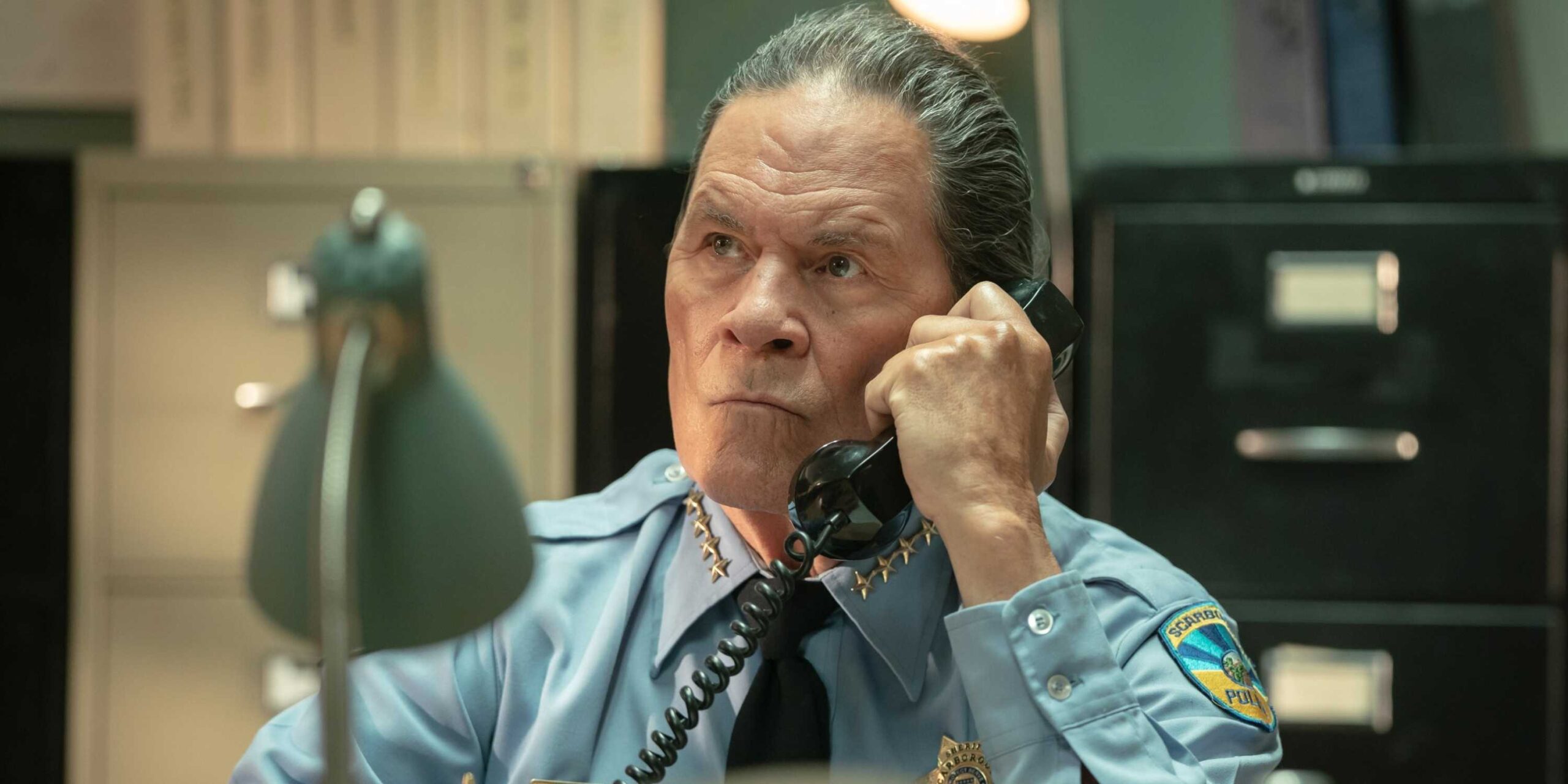 A character on the phone as they clench their jaw in Dark Winds