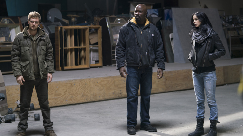 Demolidor: Renascido: Fotos sugerem Luke Cage e Punho de Ferro Finn Jones as Danny Rand standing in a warehouse next to Mike Colter as Luke Cage and Krysten Ritter as Jessica Jones in The Defenders