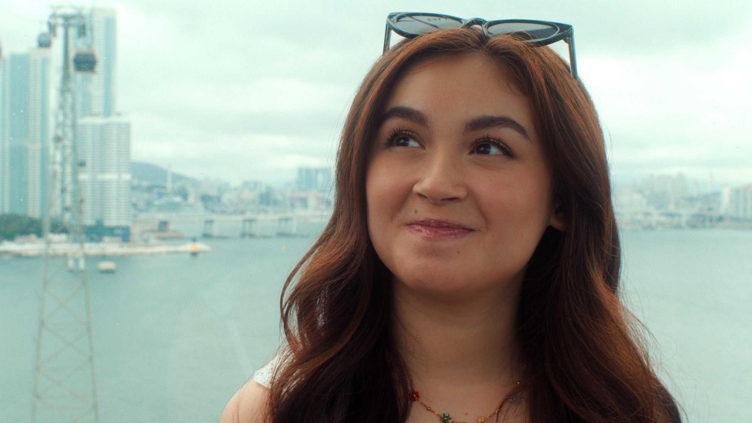 XO, Kitty: Kitty e Min Ho ficam juntos no final xo kitty season 3 still featuring kitty song covey wearing sunglasses on top of her head with the seoul skyline in the background.